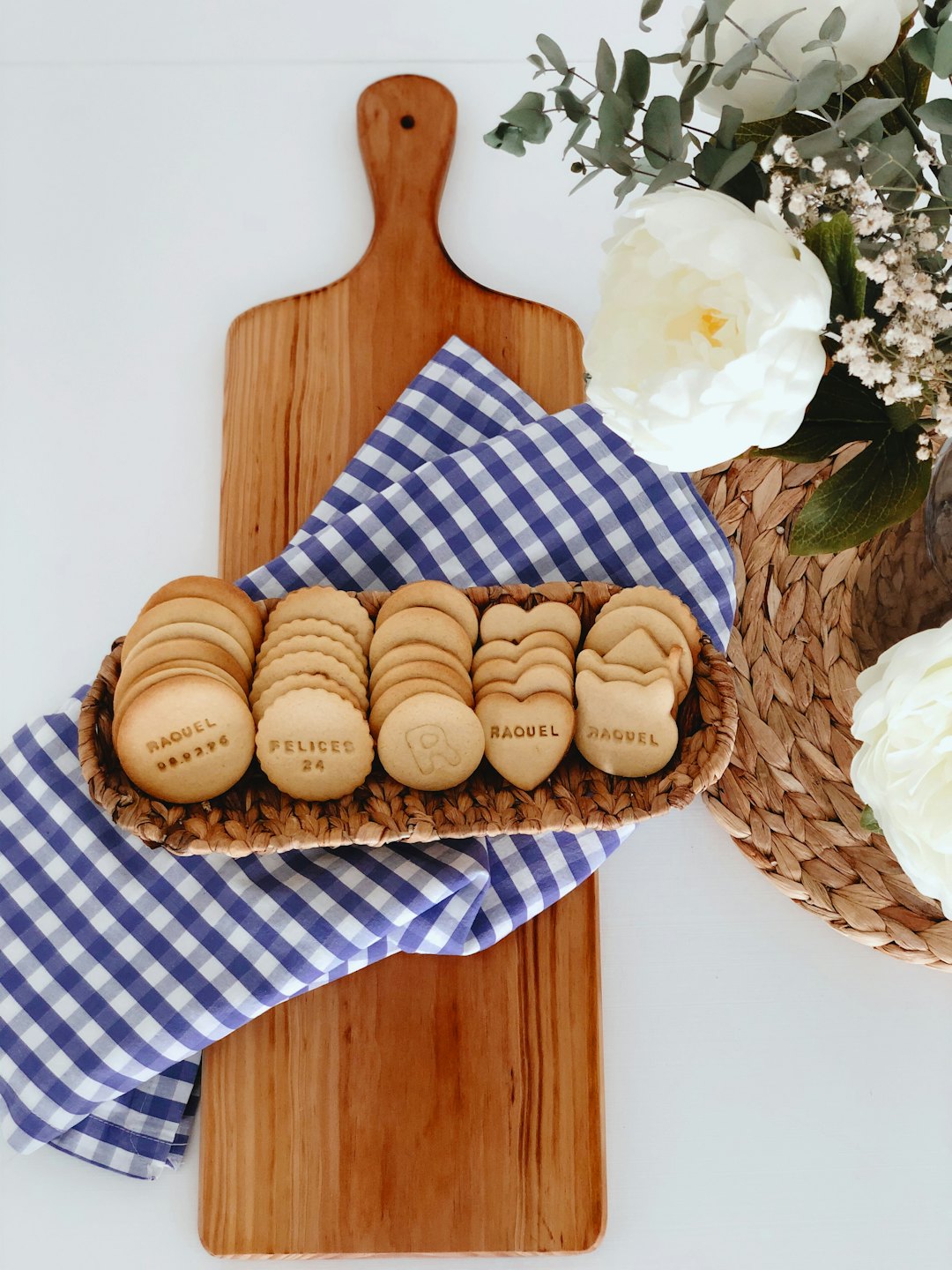 Custom sugar cookies in a wicker tray on a checkered cloth.