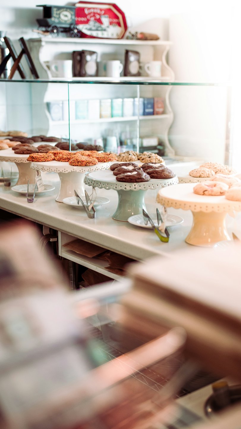Bakery display counter with cookies and baked goods on stands.