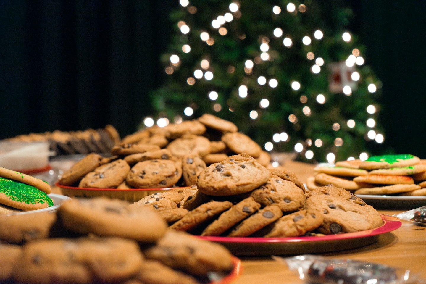 Assorted holiday cookies on plates placed on a wooden table.