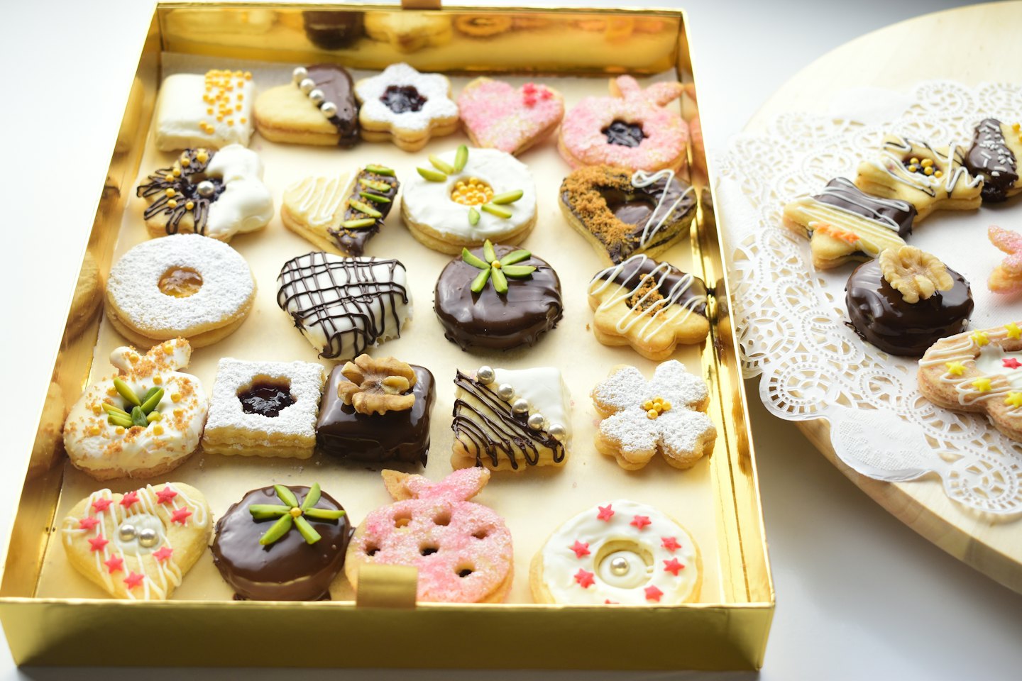 Assorted decorated pastries arranged in a golden box on a doily.